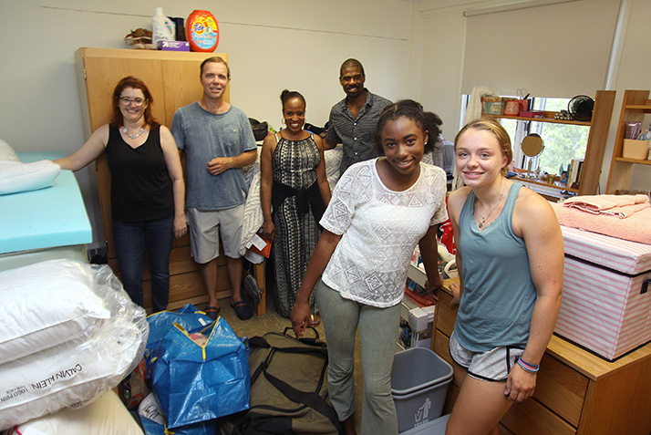 Roommates pose in front of their parents as they set up their room.