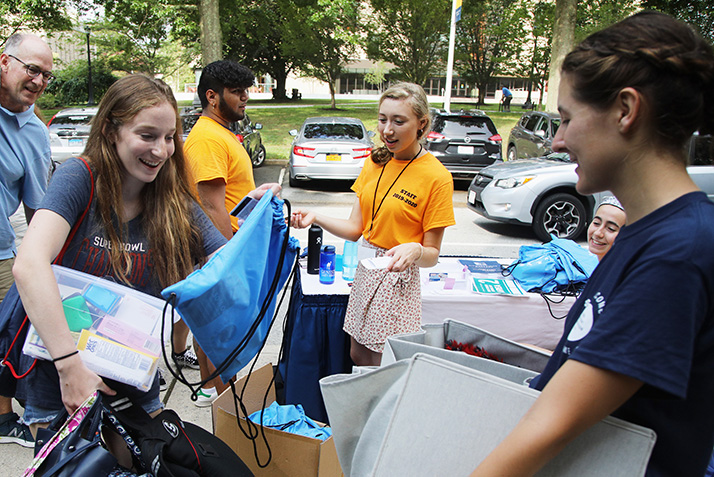 A new student pics up swag from a welcome booth. 