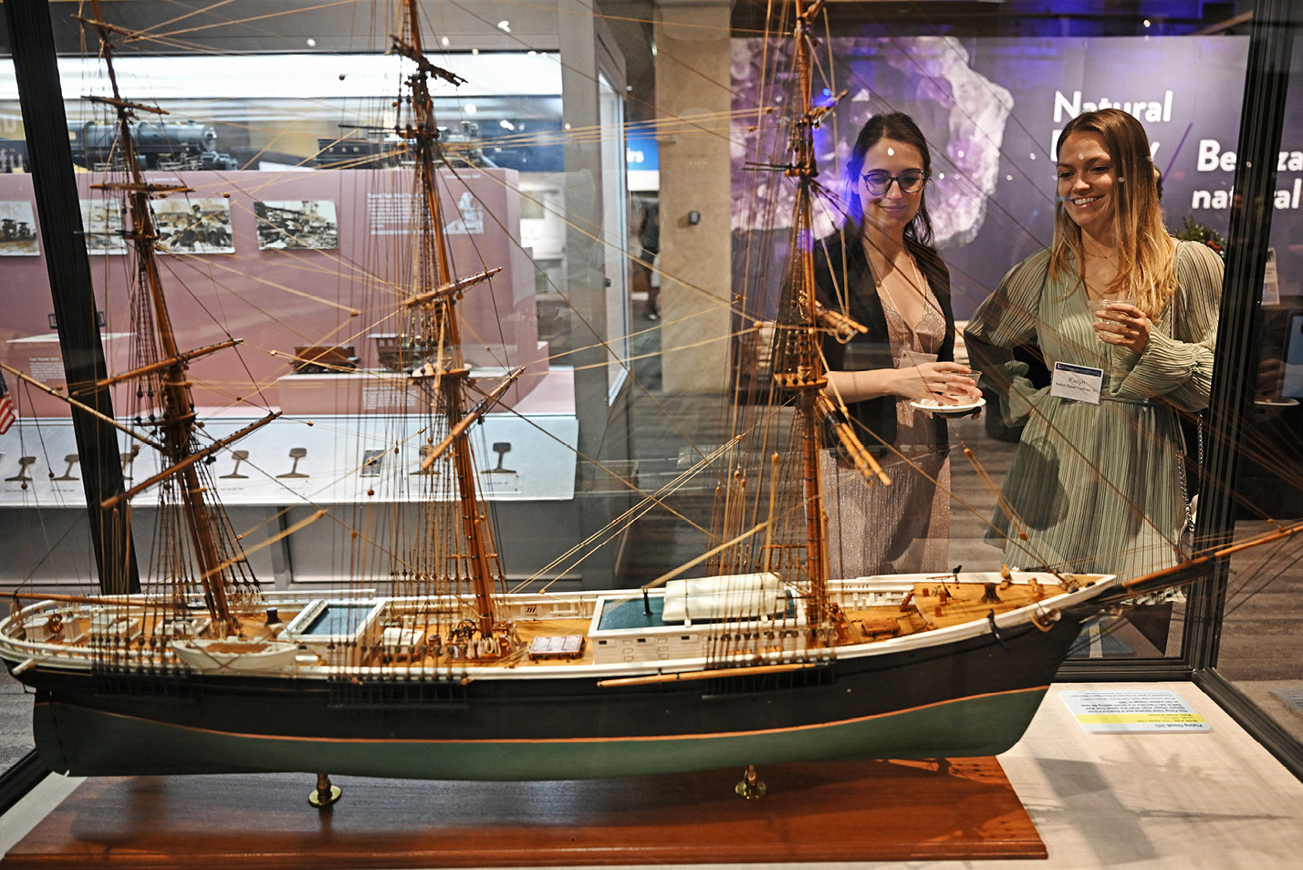 Alums looking at a ship display case at the alumni holiday party at the Boston Museum of Science.