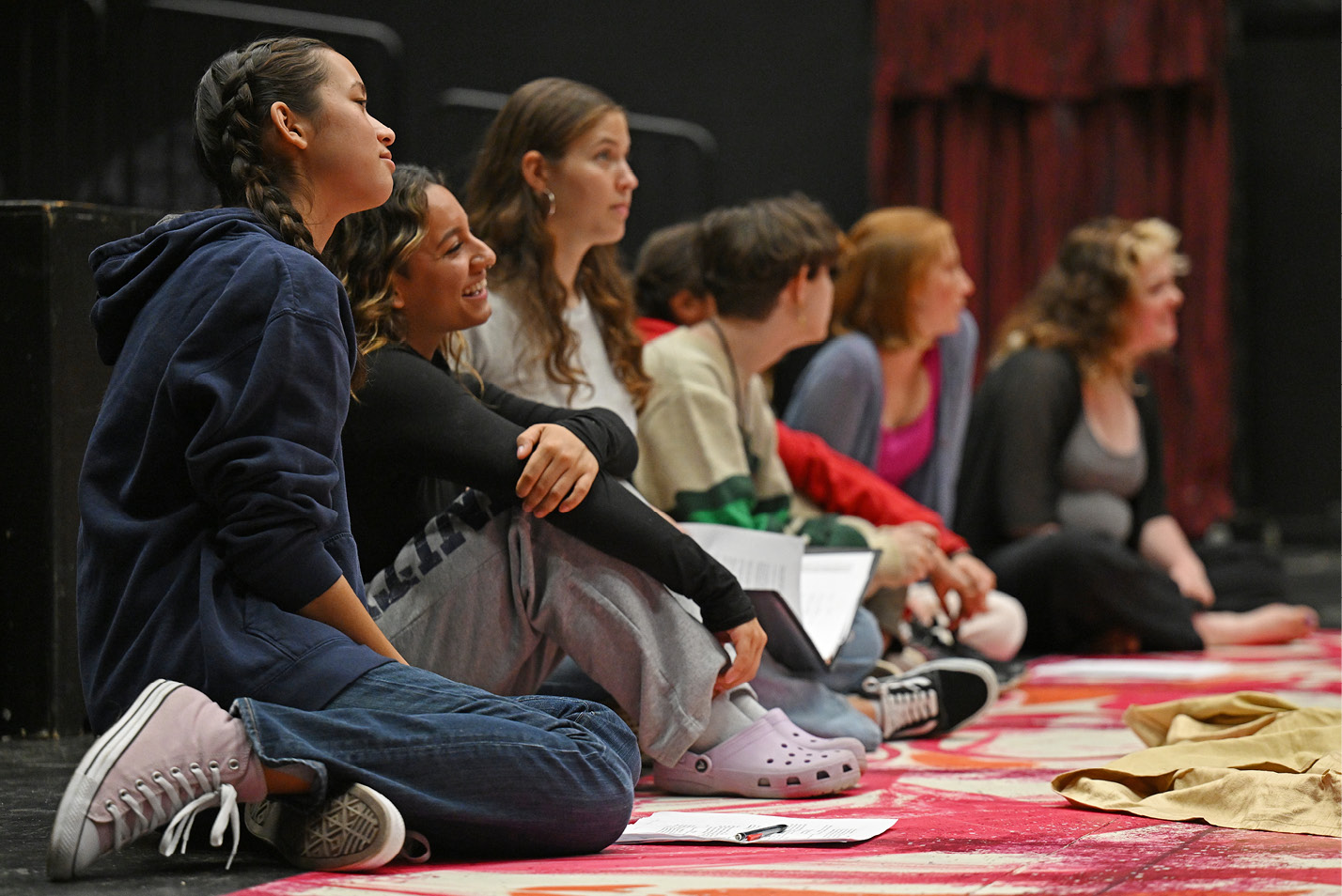 Theater students watch from the side of the stage