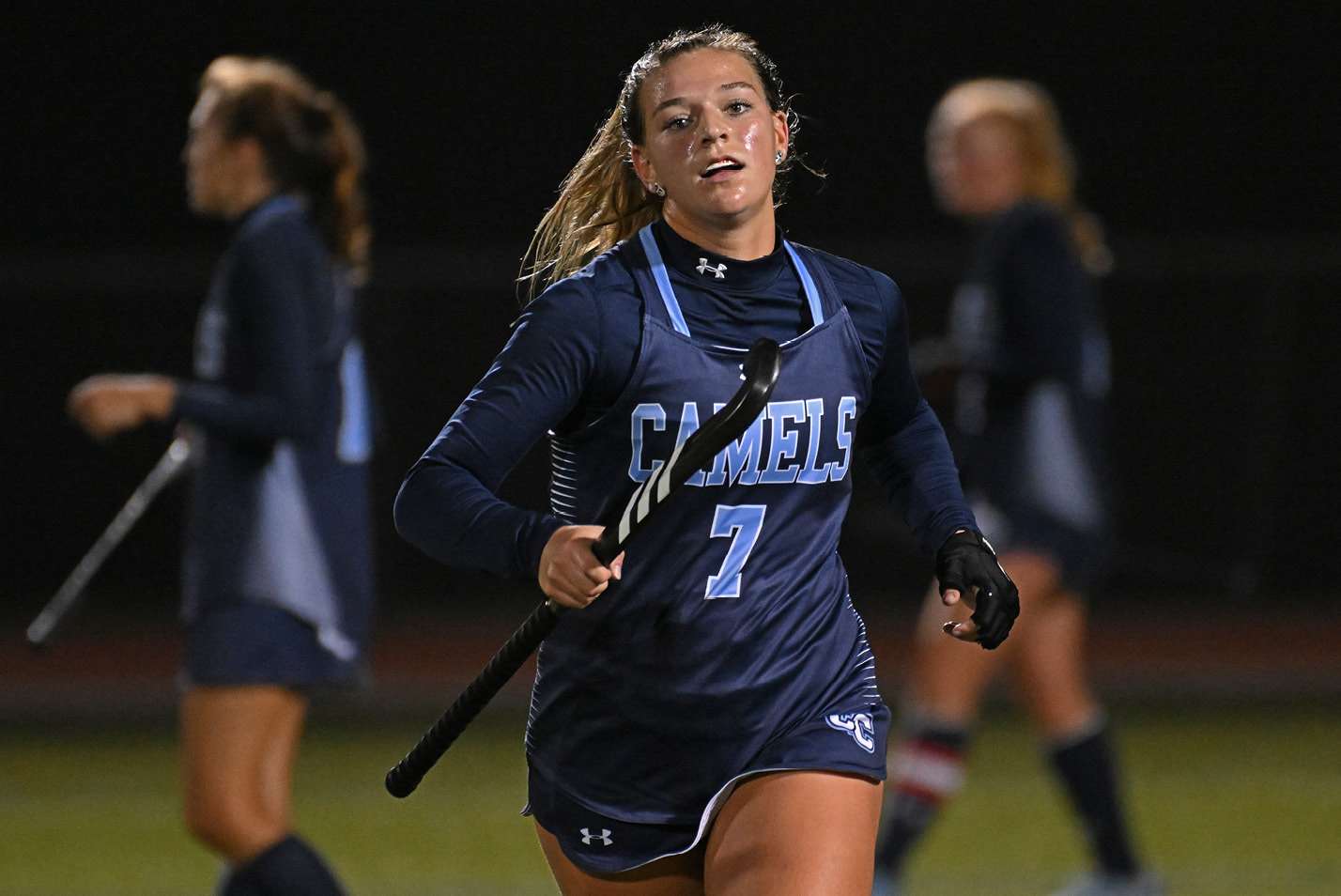 Women's field hockey player running toward camera