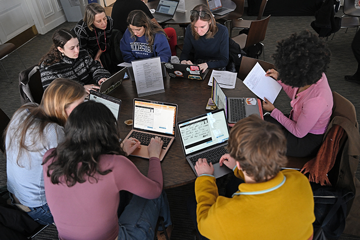 Students around circular table working on laptop computers