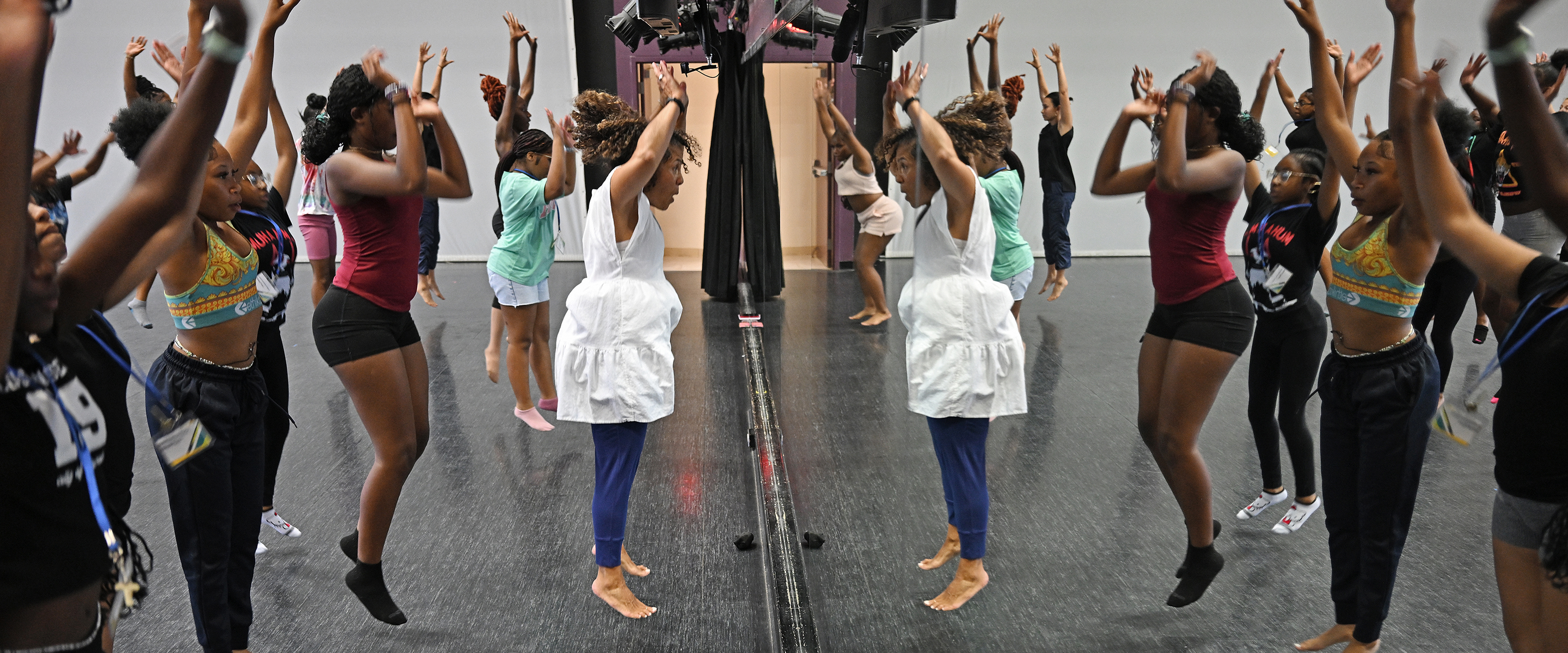 Dancers rehearse while reflected in a dance studio mirror