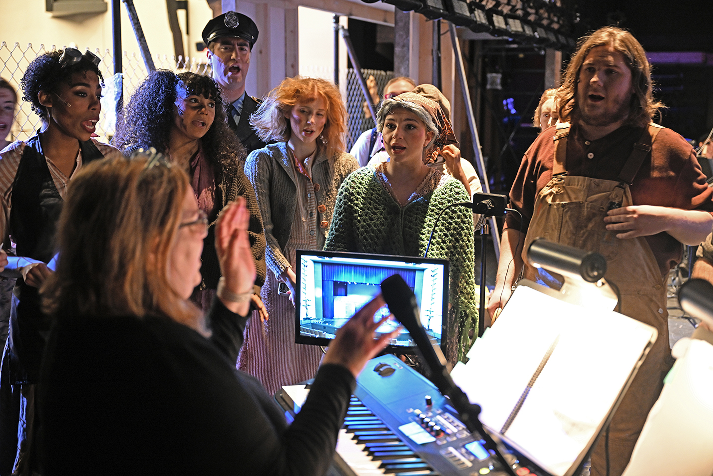 music director leads actors in vocal warm up backstage