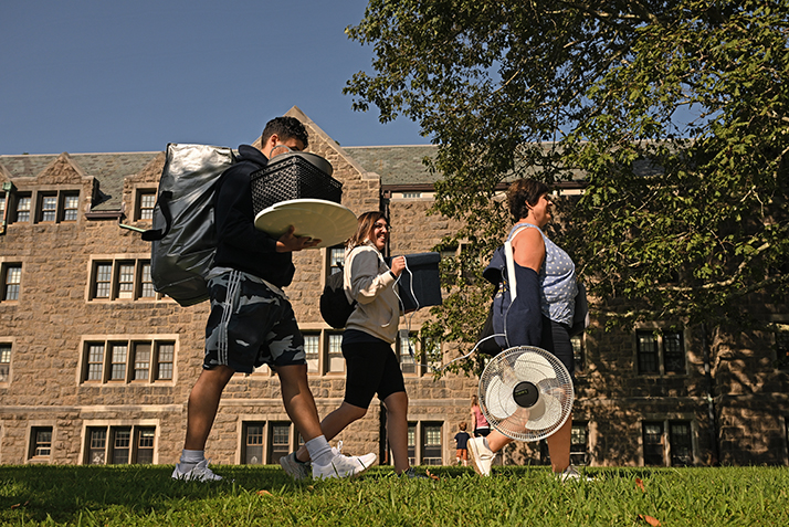 Family members help a new student carry belongs across campus.