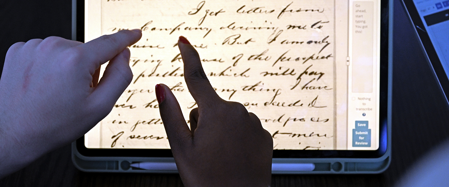 Two Douglass Day transcribers examine a word from one of the papers of Frederick Douglass.