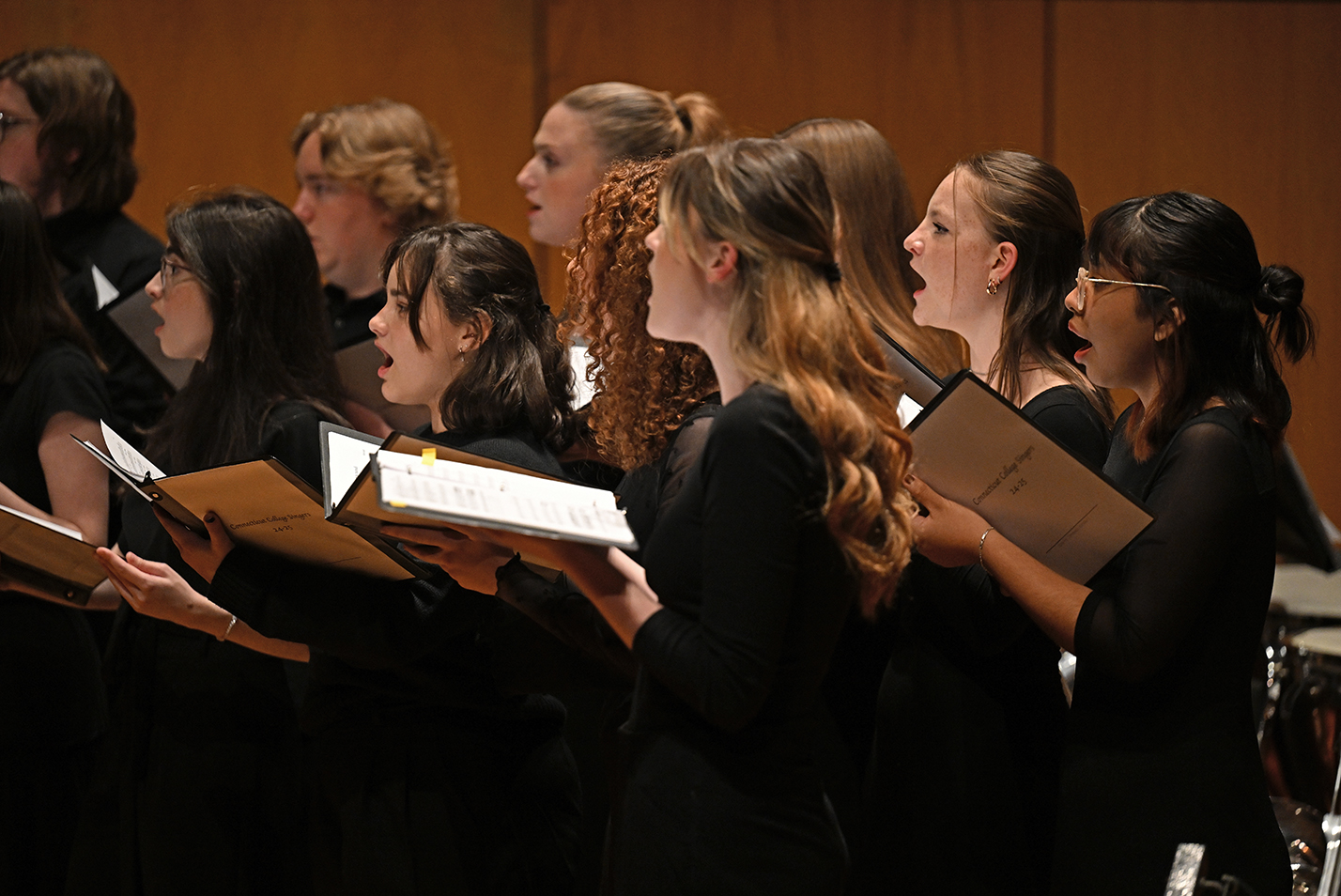 Members of a student choral group perform on stage.