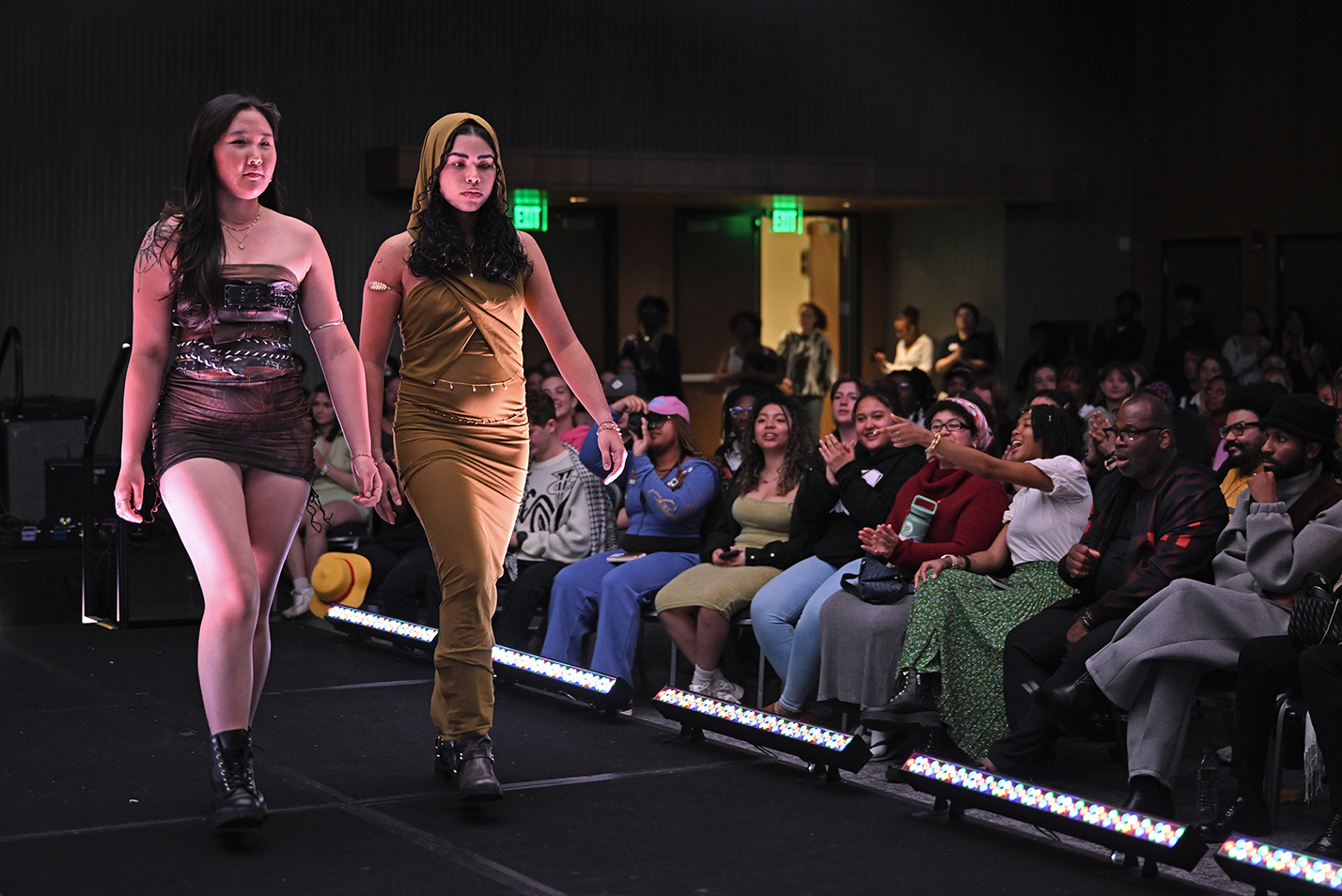 Two student models walk the stage during a fashion show.