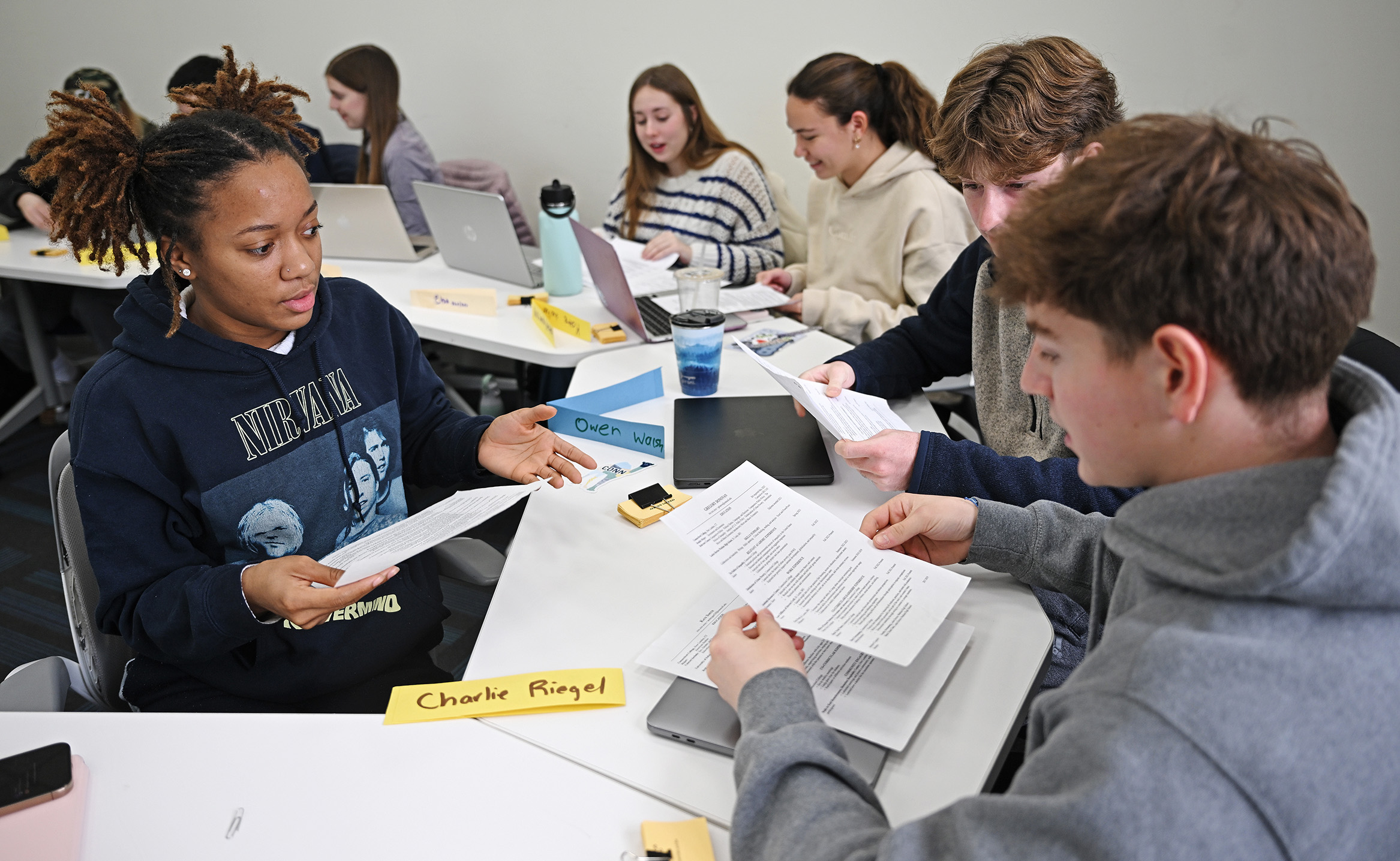 Students sitting a tables discuss documents as part of a career preparation course.